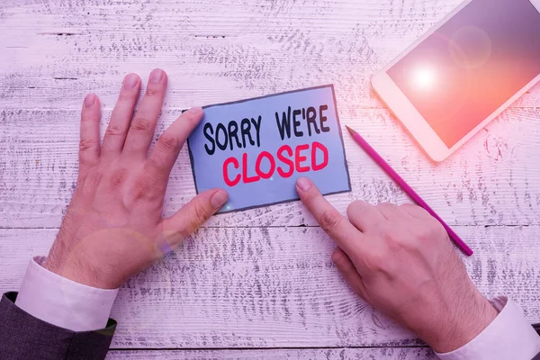 Schrijfbriefje met 'Sorry We Re Closed'. Zakelijke foto presentatie Expressie van Spijt Teleurstelling Niet Open Sign Hand houden nota papier in de buurt van het schrijven van apparatuur en smartphone. — Stockfoto