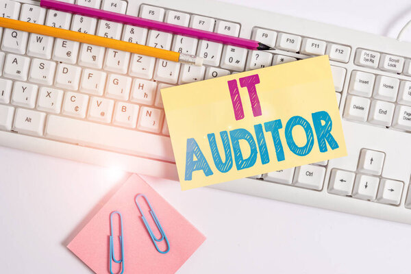 Conceptual hand writing showing It Auditor. Business photo showcasing demonstrating authorized to review and verify the accuracy of the system White keyboard with note paper and clips on white backgro