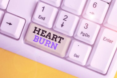 Conceptual hand writing showing Heart Burn. Business photo text a burning sensation or pain in the throat from acid reflux White pc keyboard with note paper above the white background.
