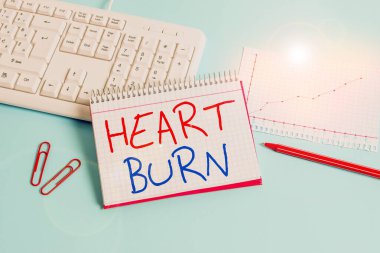 Conceptual hand writing showing Heart Burn. Business photo showcasing a burning sensation or pain in the throat from acid reflux Paper blue keyboard office study notebook chart numbers memo.