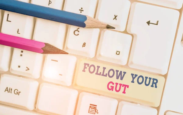 Writing note showing Follow Your Gut. Business photo showcasing Listen to intuition feelings emotions conscious perception White pc keyboard with note paper above the white background. — Stock Photo, Image