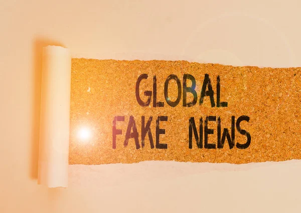 Escritura a mano conceptual que muestra Global Fake News. Foto de negocios mostrando información falsa Periodismo Mentiras Desinformación Hoax Cartón que se desgarra colocado sobre una mesa clásica de madera . — Foto de Stock
