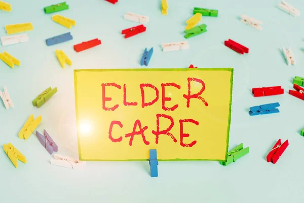 Kelime yazma Elder Care. Tıbbi sorunlar konusunda yardıma ihtiyacı olan yaşlıların bakımı için iş konsepti Renkli çamaşır iğnesi kağıtları boş hatırlatıcı mavi zemin ofis broşu. — Stok fotoğraf