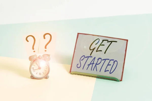 Word writing text Get Started. Business concept for Begin an important period in one s is life or career Begin a task Mini size alarm clock beside a Paper sheet placed tilted on pastel backdrop.