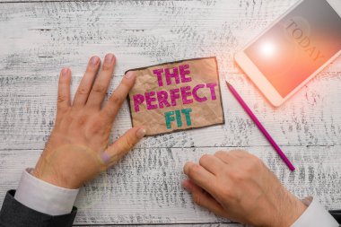 Text sign showing The Perfect Fit. Conceptual photo Puzzle pieces fitting Good teamwork Connection Integration Hand hold note paper near writing equipment and modern smartphone device.