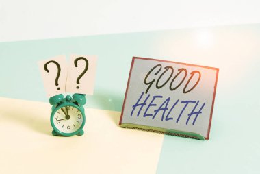 Word writing text Good Health. Business concept for state of being vigorous and free from bodily or mental disease Mini size alarm clock beside a Paper sheet placed tilted on pastel backdrop.