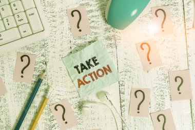 Take Action 'ı gösteren bir not yazıyorum. Özel bir sonuç elde etmek için bir şeyler yapmak için iş fotoğrafı gösterimi. Tahta masanın üstüne yazı araçları ve karalama kağıtları..