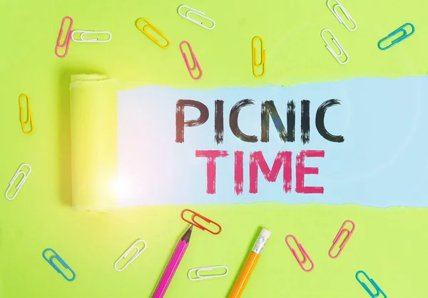 Word writing text Picnic Time. Business concept for period where meal taken outdoors as part of an excursion Stationary and torn cardboard placed above a plain pastel table backdrop.