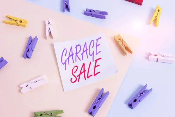 Text sign showing Garage Sale. Conceptual photo sale of miscellaneous household goods often held in the garage Colored clothespin paper empty reminder yellow blue floor background office.
