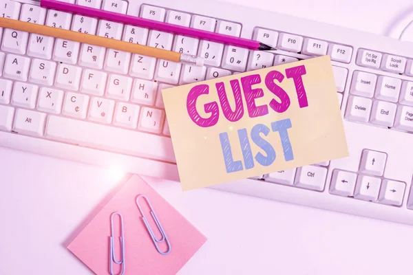 Conceptual hand writing showing Guest List. Business photo showcasing a list of showing who are allowed to enter the show or an event White keyboard with note paper and clips on white background.