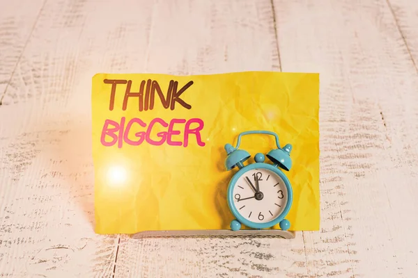 Word writing text Think Bigger. Business concept for being able to dream and visualise what you can achieve Mini blue alarm clock stand tilted above buffer wire in front of notepaper. — Stock Photo, Image