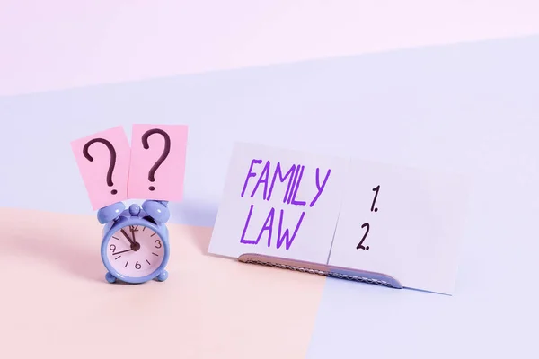 Writing note showing Family Law. Business photo showcasing the branch of law that deals with matters relating to the family Alarm clock beside a Paper sheet placed on pastel backdrop.