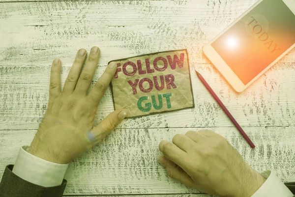 Text sign showing Follow Your Gut. Conceptual photo Listen to intuition feelings emotions conscious perception Hand hold note paper near writing equipment and modern smartphone device. — Stock Photo, Image