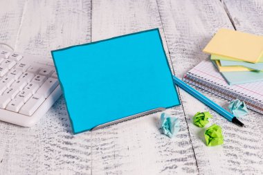 Bir klavye ve matematik kitabı arasında tampon telin üzerinde duran mavi renkli bir not kağıdı. Kalın matematik sayfaları ile yazmak için bilgisayar ekipmanlarının yanında duran eski notasyon kağıdı