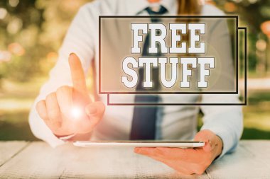 Text sign showing Free Stuff. Conceptual photo something that is given to you without you having to pay for it Female business person sitting by table and holding mobile phone.