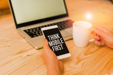 Writing note showing Think Mobile First. Business photo showcasing Easy Handheld Device Accessible Contents 24 or7 Handy woman with laptop smartphone and office supplies technology.