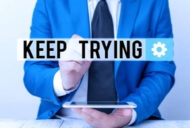 Denemeye devam ettiğini gösteren bir not yazıyorum. İş fotoğrafçılığı bir şeyler yapmaya devam ediyor ya da tekrar tekrar bir şeyler yapıyor. İşadamı boş kopya alanını kalemle işaret ediyor..