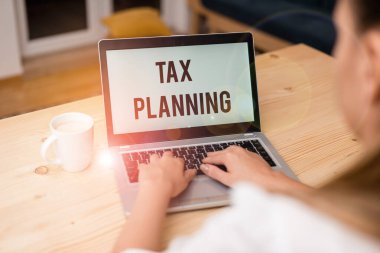 Vergi Planlama 'yı gösteren bir not yazıyorum. Finansal durumun iş fotoğraflarının gösterilmesi ya da vergi perspektifinden akıllı telefon ve ofis teknolojisi olan bir kadın tarafından planlanması.