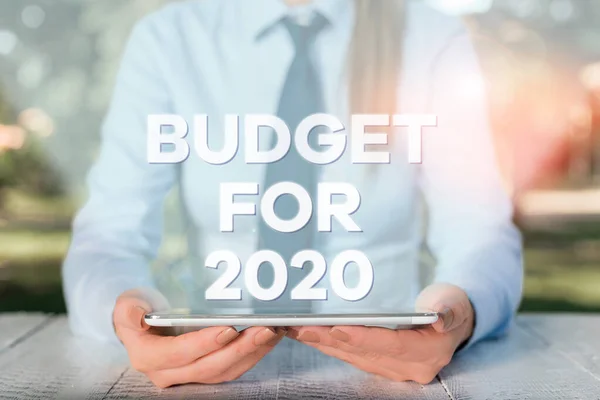 Написання тексту Бюджет на 2020 рік. Концепція значення Письмові оцінки доходів і витрат на 2020 рік Жіночий бізнесмен сидить за столом і тримає мобільний телефон . — стокове фото