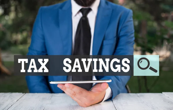 Word writing text Tax Savings. Business concept for only a portion of income is taxable Pay a reduced amount of tax Businessman with mobile phone in his hand.