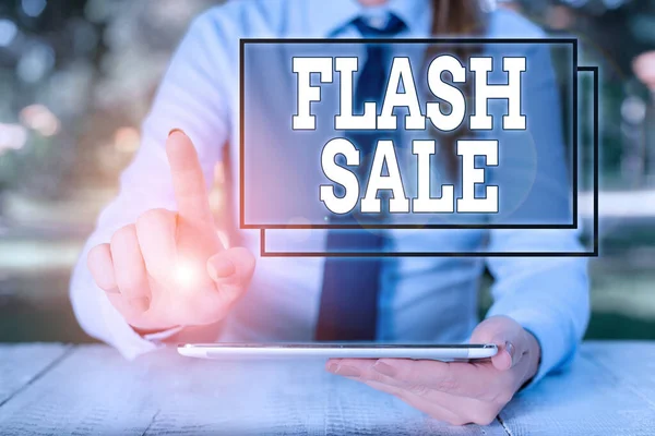 Text sign showing Flash Sale. Conceptual photo a sale of goods at greatly reduced prices at a short period Female business person sitting by table and holding mobile phone.