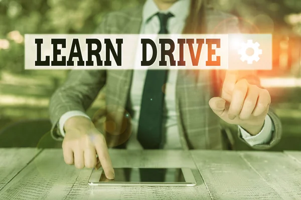 Handwriting text writing Learn Drive. Concept meaning to gain the knowledge or skill in driving a motor vehicle Female business person sitting by table holding mobile phone.