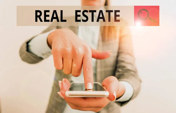 Writing note showing Real Estate. Business photo showcasing the property consisting of land and the buildings on it Business woman points with finger on touch screen.