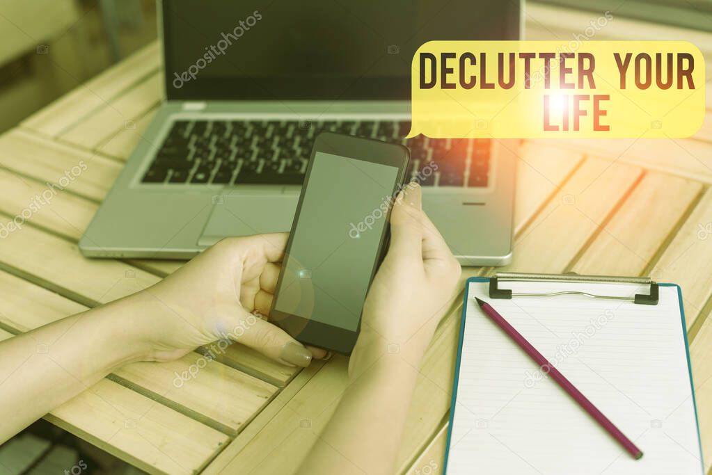 Handwriting text Declutter Your Life. Concept meaning To eliminate extraneous things or information in life woman laptop computer smartphone office supplies technological devices.