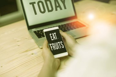 Text sign showing Eat Fruits. Conceptual photo consume any product of plant growth useful to huanalysiss or animals woman laptop computer smartphone mug office supplies technological devices.