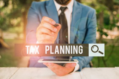 El yazısı Vergi Planlama. Finansal durumun analizi anlamına gelen kavram ya da vergi perspektifinden bir iş adamı boş kopya alanını kalemle işaret ediyor.