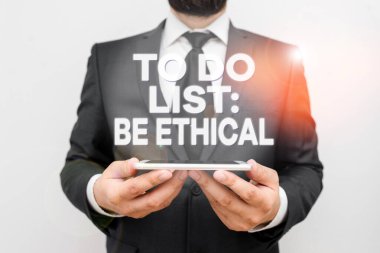 Text sign showing To Do List Be Ethical. Conceptual photo plan or reminder that is built in an ethical culture Male human wear formal work suit hold smart hi tech smartphone use hands.