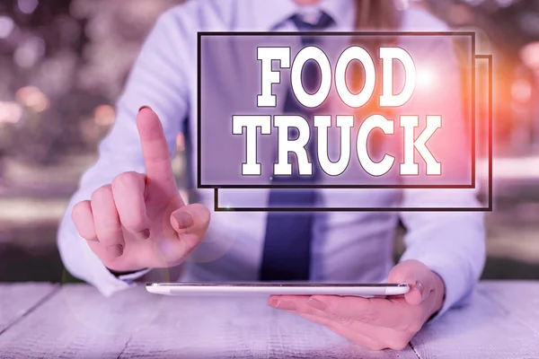 Text sign showing Food Truck. Conceptual photo a large vehicle with facilities for cooking and selling food Female business person sitting by table and holding mobile phone. — Stock Photo, Image