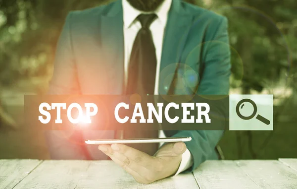 Word writing text Stop Cancer. Business concept for prevent the uncontrolled growth of abnormal cells in the body Businessman with mobile phone in his hand.