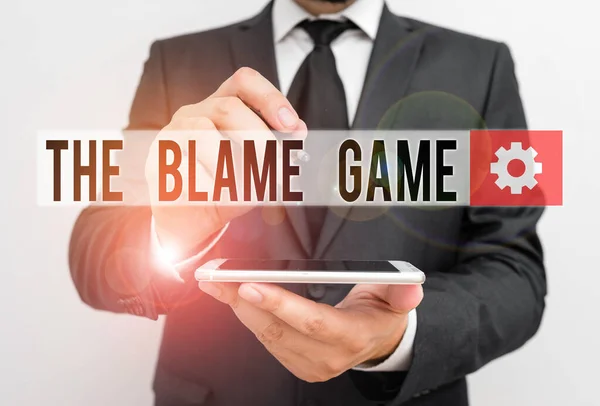 Segno di testo che mostra The Blame Game. Foto concettuale Una situazione quando si mostra il tentativo di biasimarsi l'un l'altro Maschio vestito da lavoro formale tenere smart hi tech smartphone utilizzare una mano . — Foto Stock