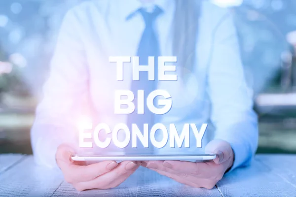 Handwriting text writing The Big Economy. Concept meaning Global finances Worldwide Market Trade Money exchange Female business person sitting by table and holding mobile phone. — Stock Photo, Image