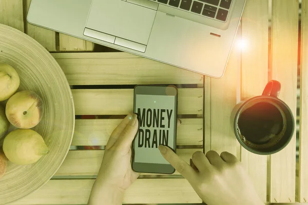 Handwriting text writing Money Drain. Concept meaning To waste or squander money Spend money foolishly or carelessly woman computer smartphone drink mug office supplies technological devices. — ストック写真