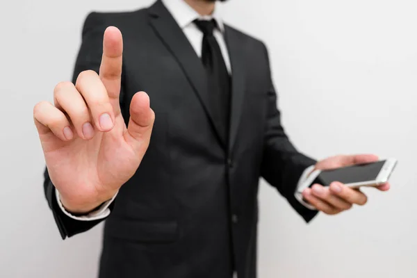 Homem com barba usar roupas de trabalho formais segurar dispositivo de smartphone de alta tecnologia. Homem vestido em terno de trabalho mais gravata segurando pequeno celular oi telefone usando uma mão — Fotografia de Stock