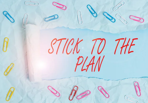 Text sign showing Stick To The Plan. Conceptual photo To adhere to some plan and not deviate from it Follow Paper clip and torn cardboard placed above a plain pastel table backdrop.