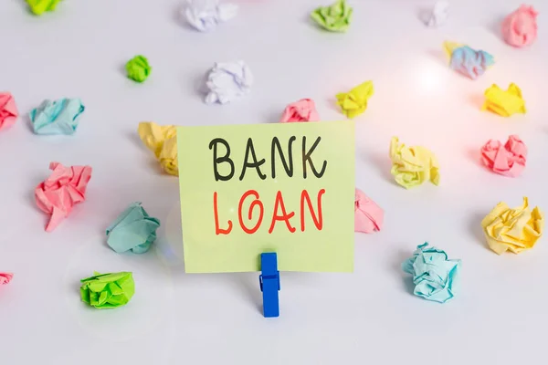 Word writing text Bank Loan. Business concept for an amount of money loaned at interest by a bank to a borrower Colored crumpled papers empty reminder white floor background clothespin.
