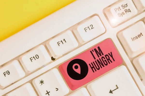 Writing note showing I M Hungry. Business photo showcasing having a strong wish or desire for something to put on stomach White pc keyboard with note paper above the white background.