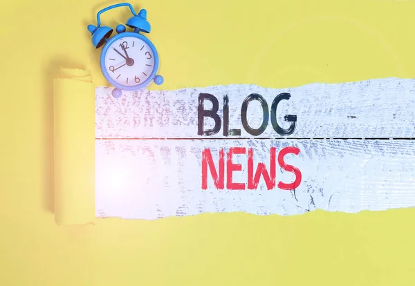 Conceptual hand writing showing Blog News. Business photo text regularly updated website typically one run by an individual Alarm clock and torn cardboard on a wooden classic table backdrop.