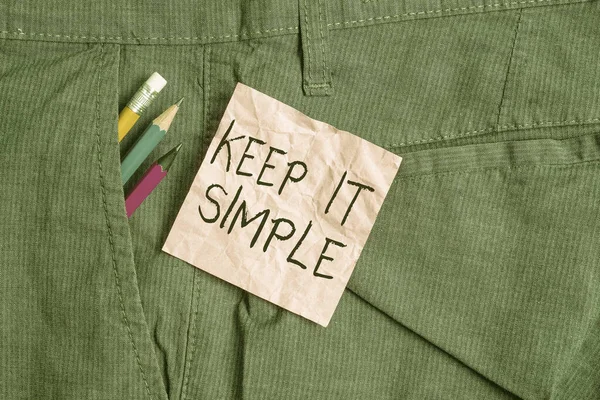 Text sign showing Keep It Simple. Conceptual photo Remain in the simple place or position not complicated Writing equipment and pink note paper inside pocket of man work trousers.