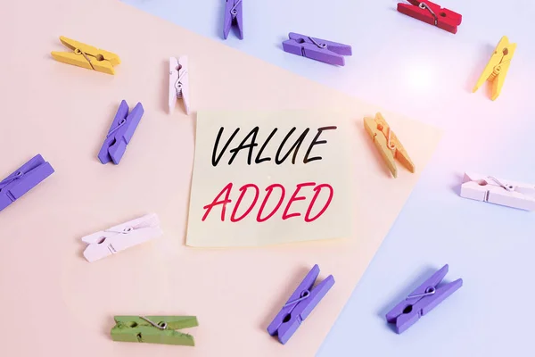 Word writing text Value Added. Business concept for the extra value created over and above the original value Colored clothespin paper empty reminder yellow blue floor background office.