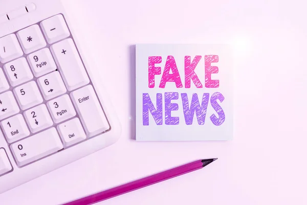 Handschriftliche Fake News. Konzept bedeutet, Informationen zu geben, die durch die weiße PC-Tastatur der Medien mit leerem Notizpapier und Bleistift über weißem Hintergrund nicht stimmen.. — Stockfoto
