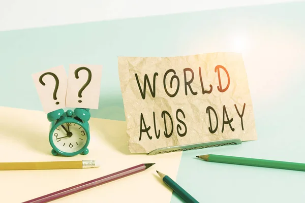 Conceptual hand writing showing World Aids Day. Business photo showcasing 1st December dedicated to raising awareness of the AIDS Mini size alarm clock beside stationary on pastel backdrop. — Stockfoto