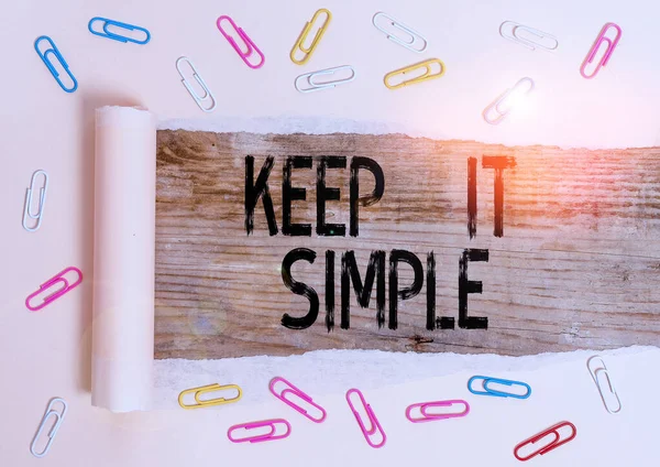 Conceptual hand writing showing Keep It Simple. Business photo showcasing Remain in the simple place or position not complicated Paper clip and torn cardboard on wood classic table backdrop.