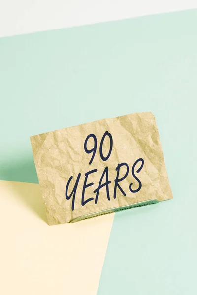 Woord schrijven tekst 90 Jaar. Business concept voor Herinneren of eren van speciale dag voor 90 jaar bestaan Papier gekanteld boven bufferdraad op zachte pastel multi kleuren achtergrond. — Stockfoto