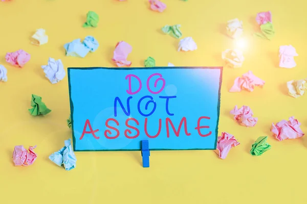 Text sign showing Do Not Assume. Conceptual photo Ask first to avoid misunderstandings confusion problems Colored crumpled papers empty reminder white floor background clothespin. — Stockfoto