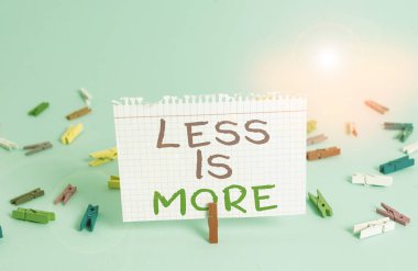 Word writing text Less Is More. Business concept for Minimalist approach to artistic matter is more effective Colored clothespin rectangle square shaped paper light blue background.