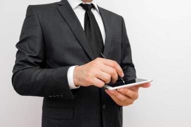 Sakallı bir erkek resmi iş kıyafetleri giyer yüksek teknoloji akıllı telefon cihazı taşır. İş elbisesi giymiş bir adam ve kravatlı küçük cep telefonlu bir adam tek elini kullanıyor.